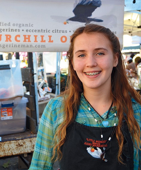 A Churchill Orchard worker greets shoppers with a smile and many varieties of citrus and avocados.